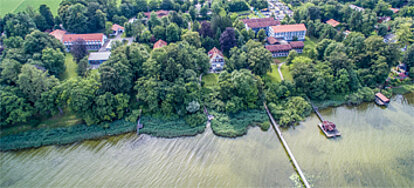 Auf dem Foto aus der Vogelperspektive sieht man die vielen unterschiedlichen Gebäude des BVS-Bildungszentrum Holzhausen mit vielen grün belaubten Bäumen.